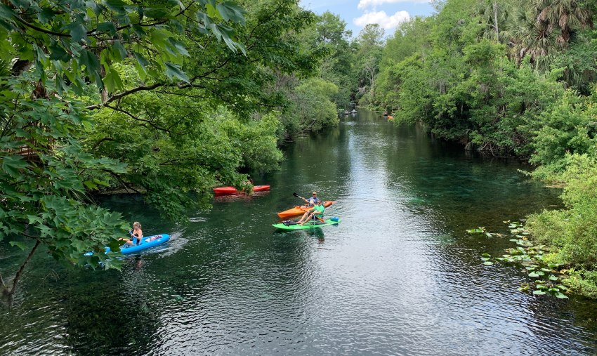 Several kayaks paddled on the river by a group of people