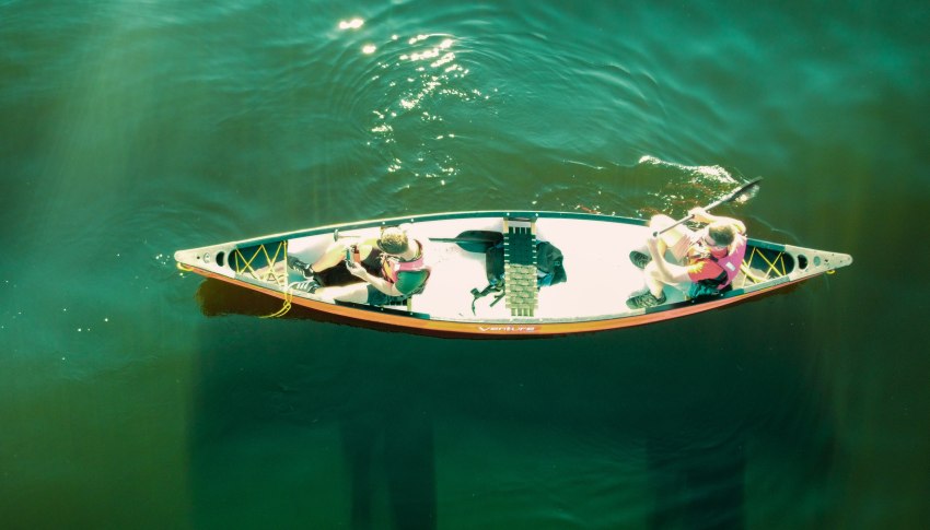 Two men in a canoe on green water