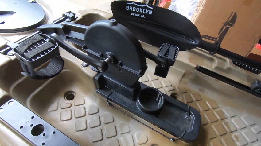 The BKC PKDRIVE kayak pedal system and a pedal drive opening’s cover with a cup holder and a small tray on the BKC PK11 kayak