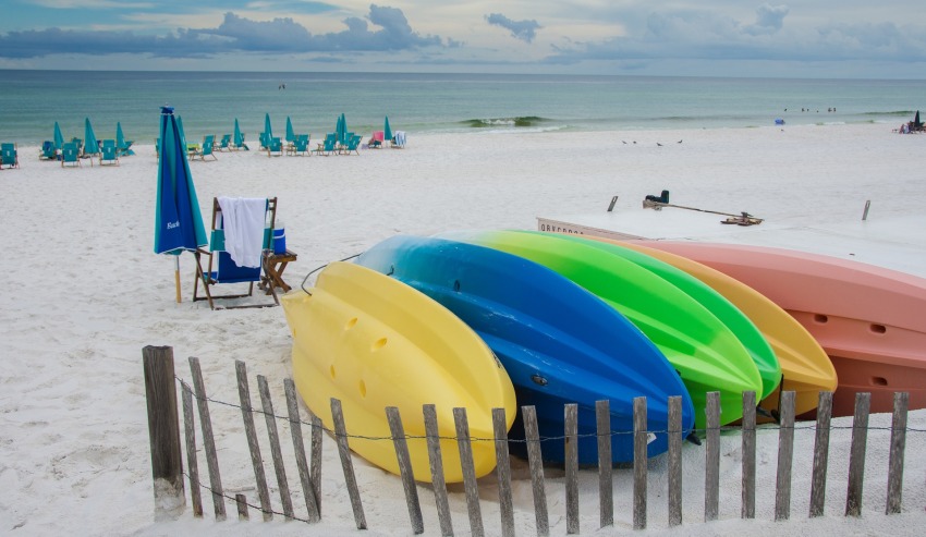 Plastic kayaks of different colors lie on the beach
