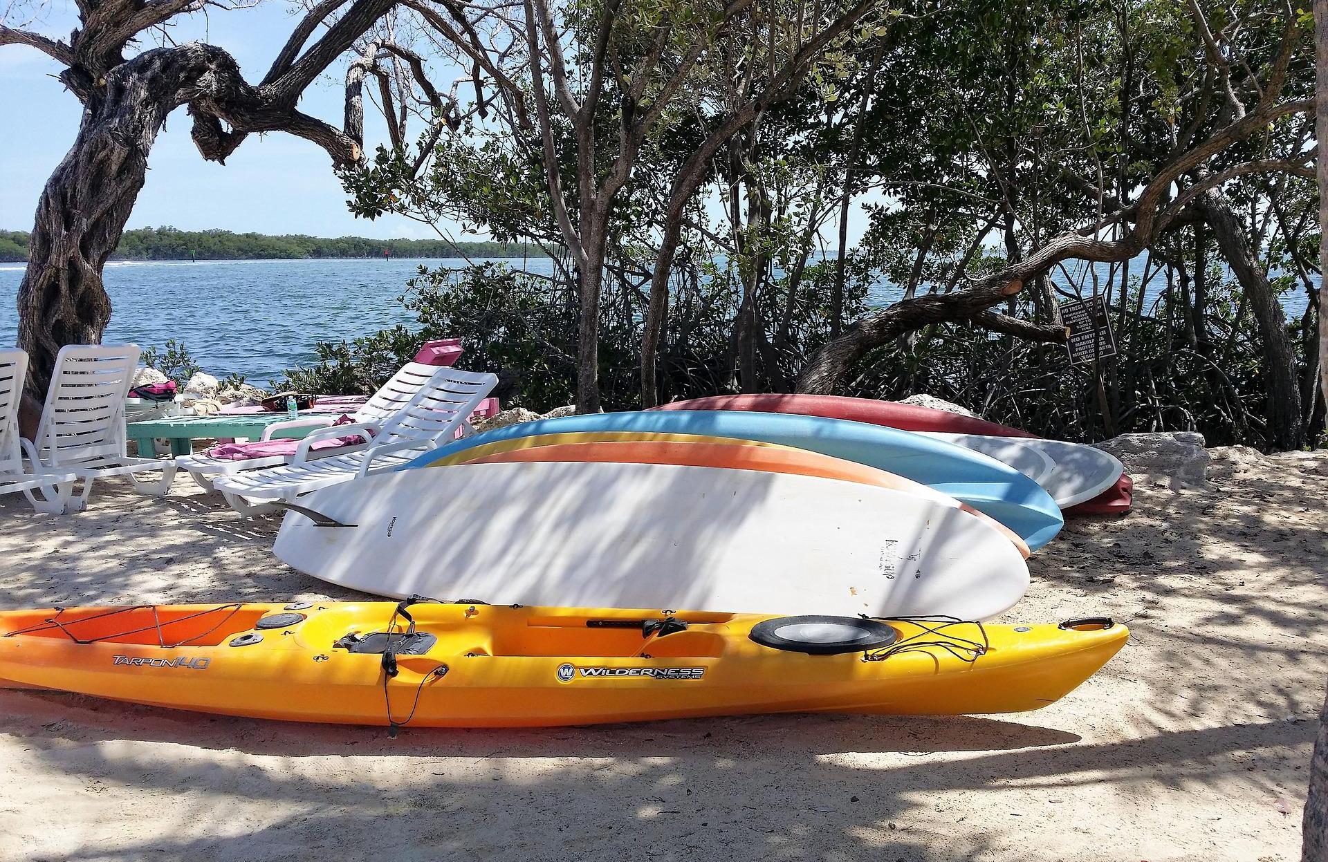 A yellow kayak and several paddleboards lie on the beach