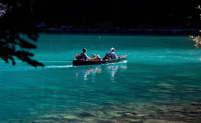 A family paddles their canoe on blue water