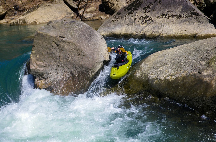 A man paddles a yellow kayak in whitewater