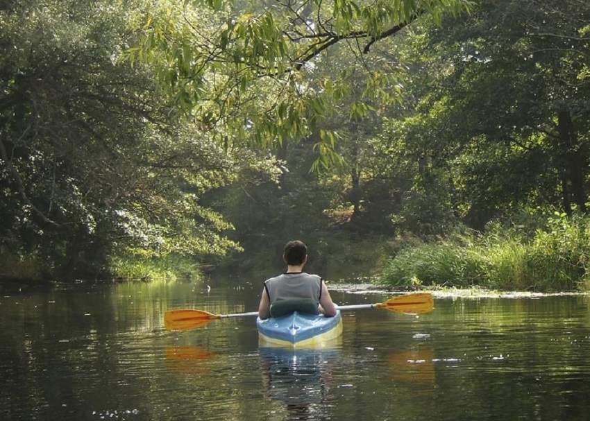 A man paddles a blue and yellow kayak  on Green River in Mammoth Cave National Park