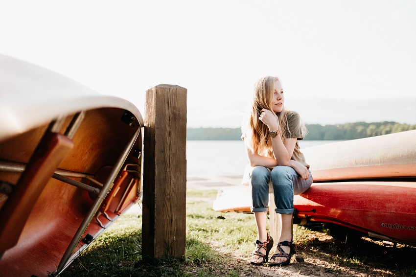 A girl sits on a red canoe and stares into the distance