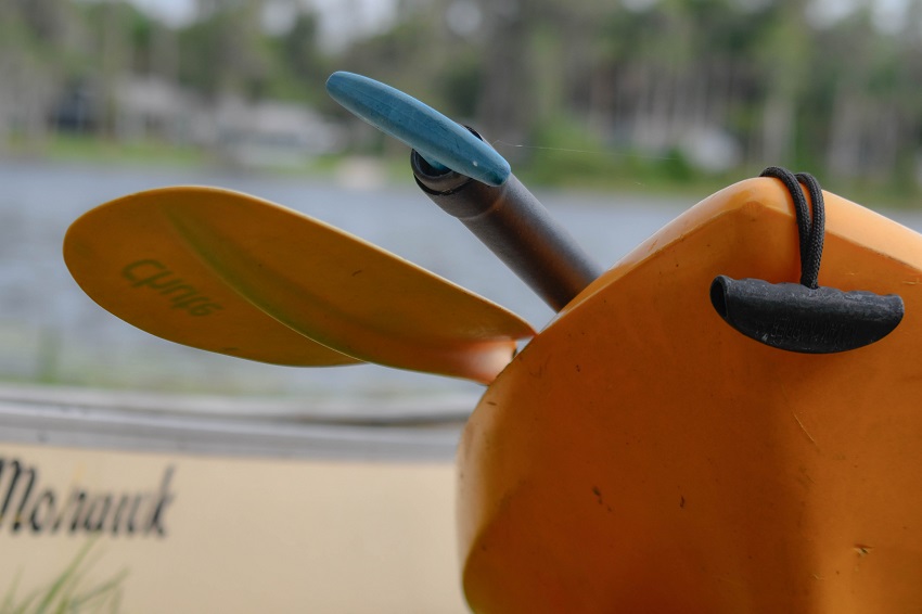 A bow of a yellow kayak with two paddles on it