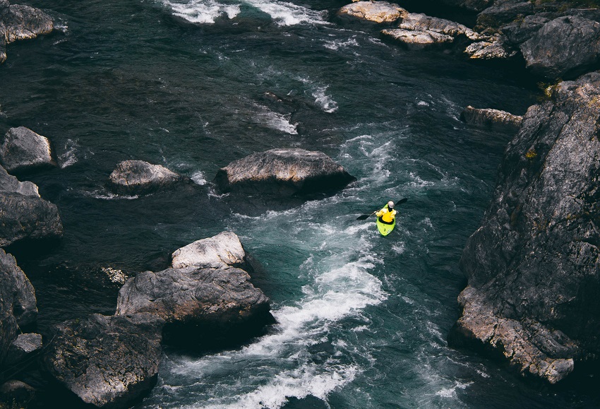 A man paddles a yellow kayak in the whitewater