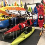 Multiple kayaks of different colors stored on racks in a kayak shop