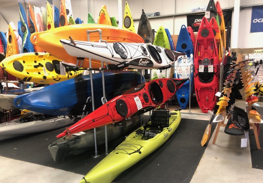 Multiple kayaks of different colors stored on racks in a kayak shop