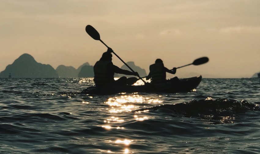 Two people paddle their kayaks in open waters