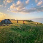 A family plays near a tunnel tent at sunset
