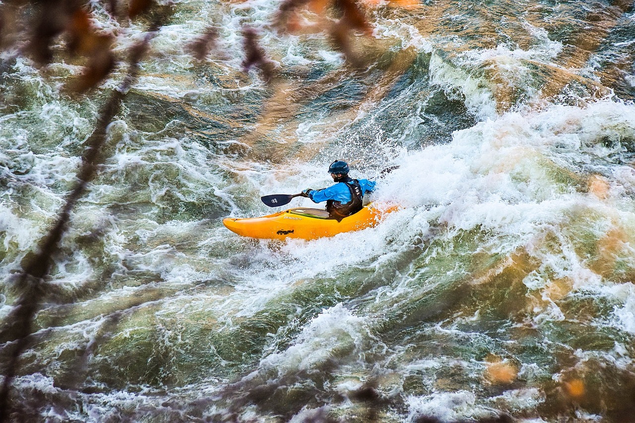 A man paddles a yellow kayak in the whitewater