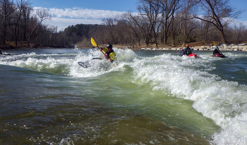 A group of kayakers paddles in white waters of the Siloam Springs Kayak Park