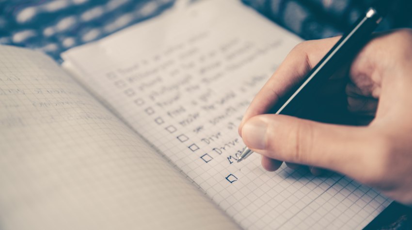 A human hand checks a list with a pen