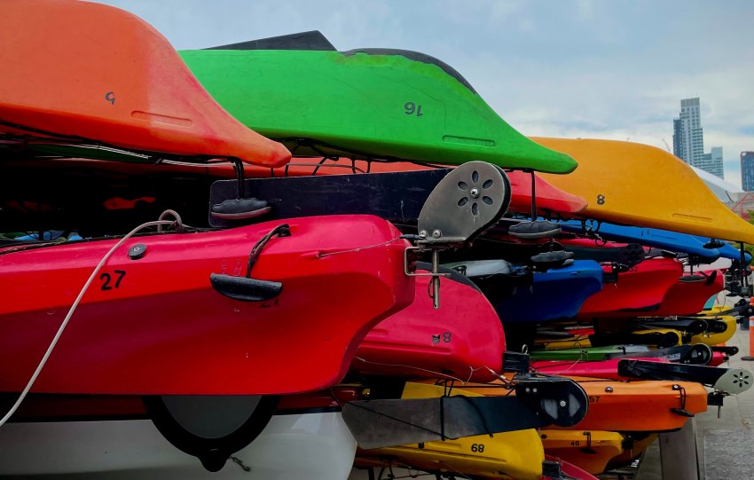 Multiple kayaks of different colors are stored on racks