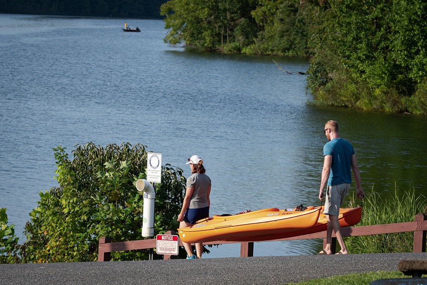 A man and a woman carry two yellow kayaks to the water