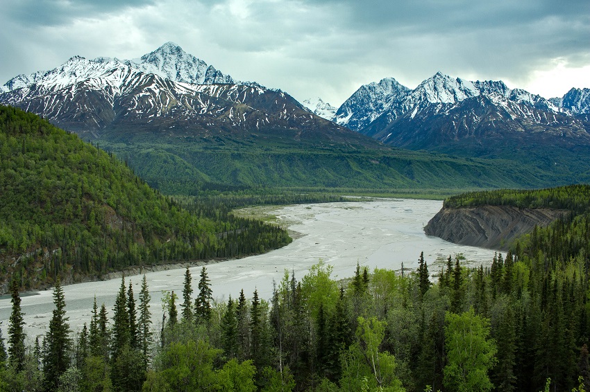 The river flows between snowy mountains in Alaska