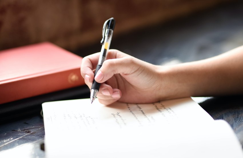 A human hand with a pen makes notes in a notebook 