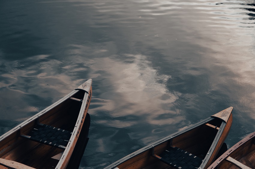 Three wooden canoes are on water