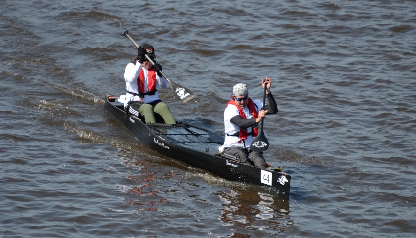 A couple in red life vests paddles a racing canoe