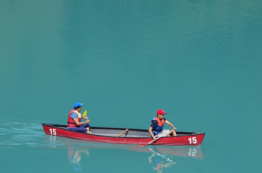 Two men paddle a red tandem canoe in open water 