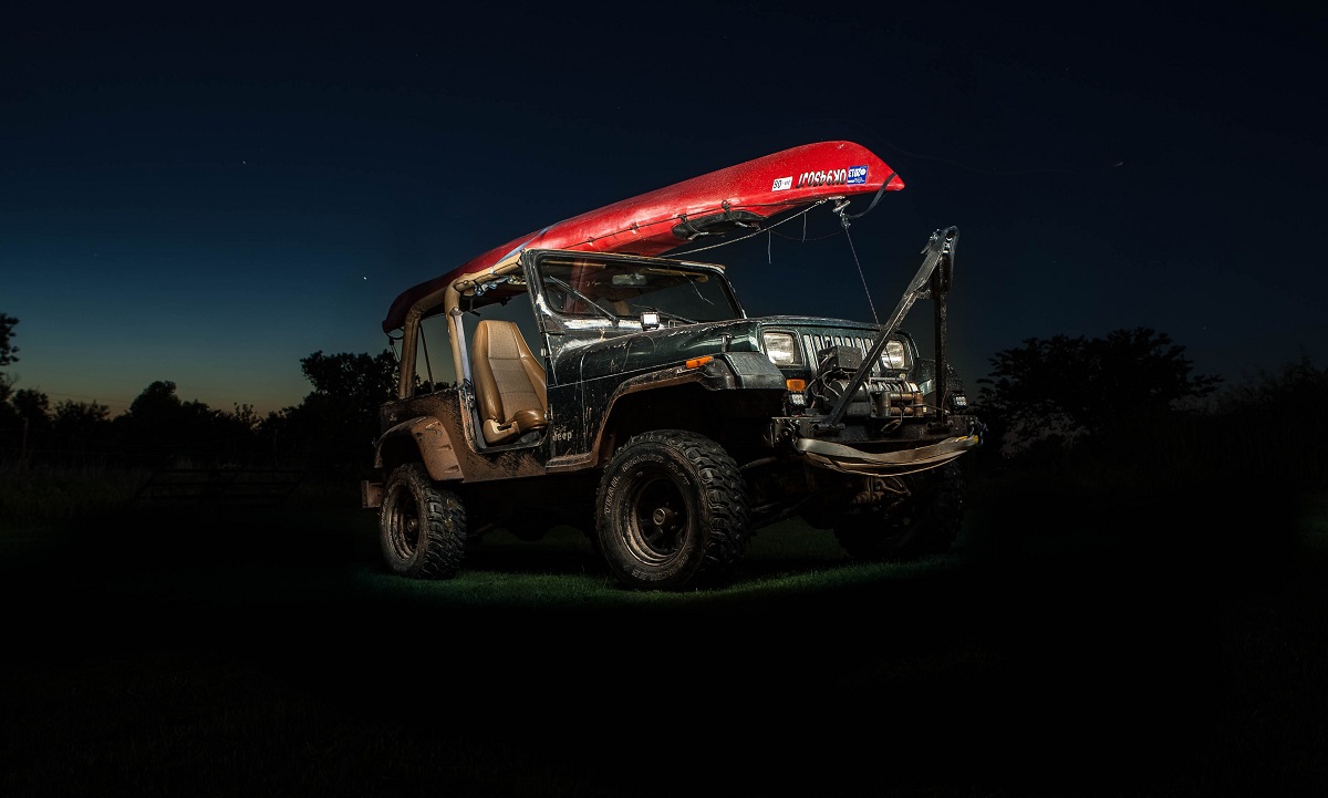 An off-road vehicle with a red kayak on its roof