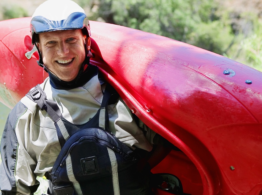 A man carries a red plastic kayak on his shoulder