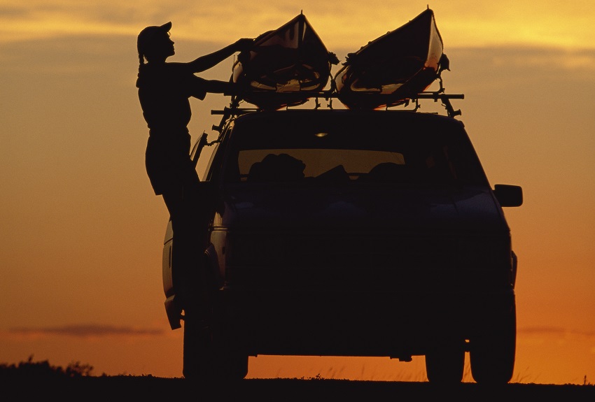 A woman loads two kayaks onto a vehicle