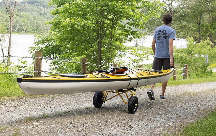 A man transports his yellow kayak on a cart
