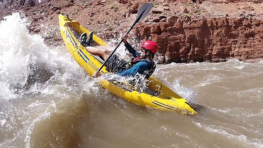 A man paddles his yellow kayak in the whitewater