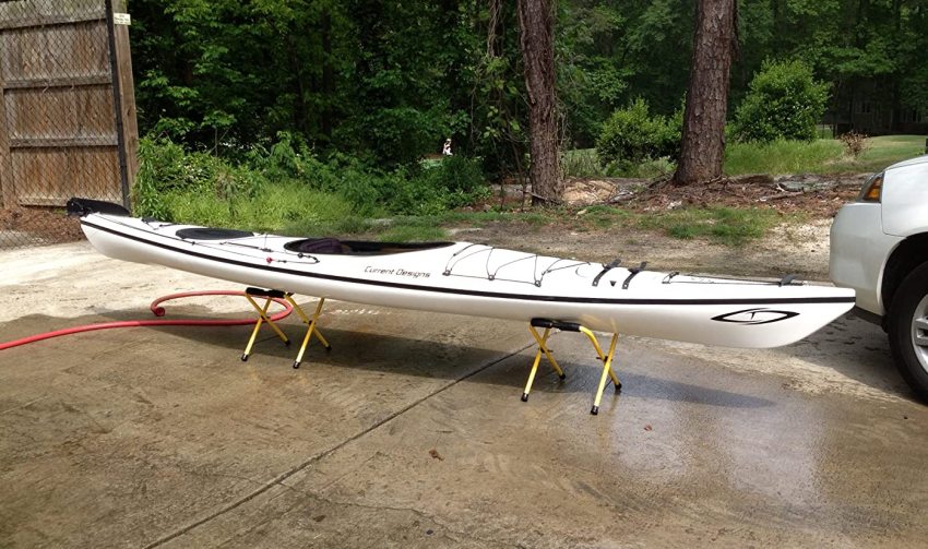 A long white kayak rests on two collapsible racks