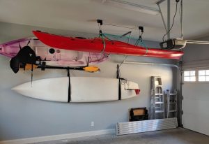 Two kayaks and a SUP stored in a garage