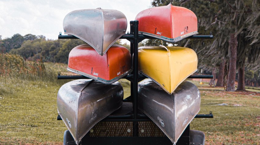 Six aluminum canoes are stored on a rack