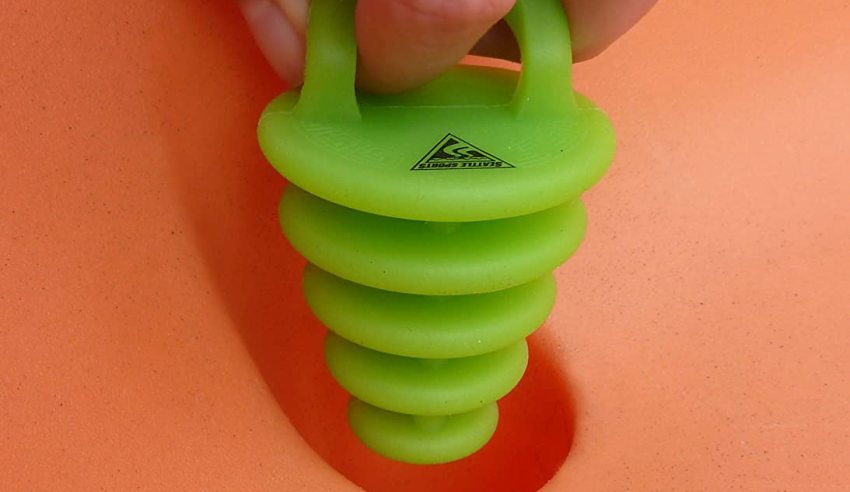 Human fingers hold a green scupper plug