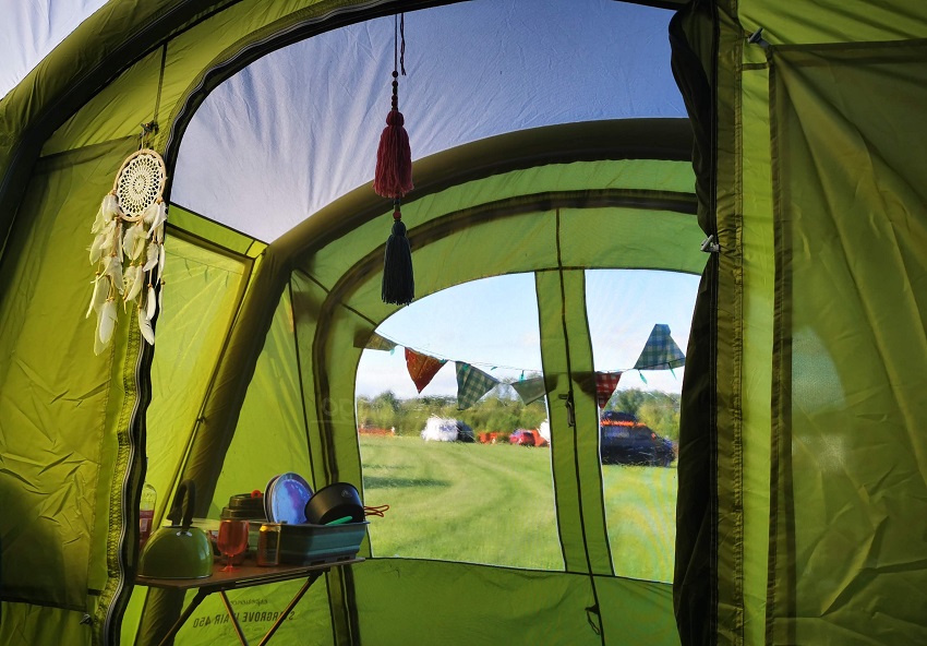 A kitchen inside a screen room of a green camping tent