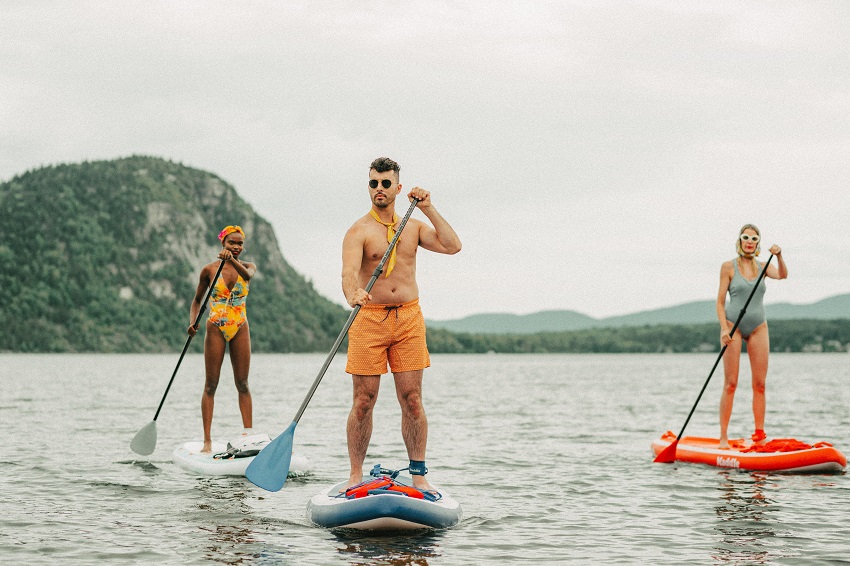 Two women and a man paddle stand up paddle boards on open water