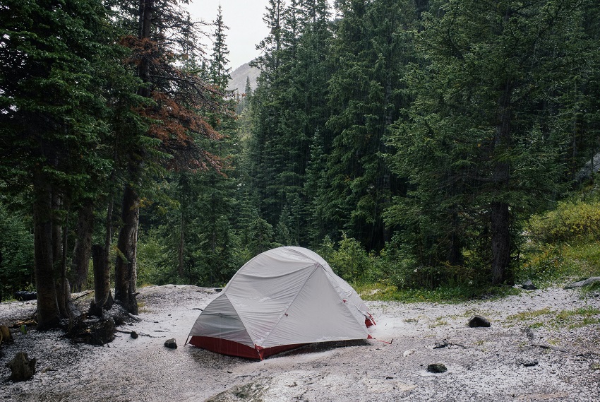 A tent with a gray rainfly pitched in a forest