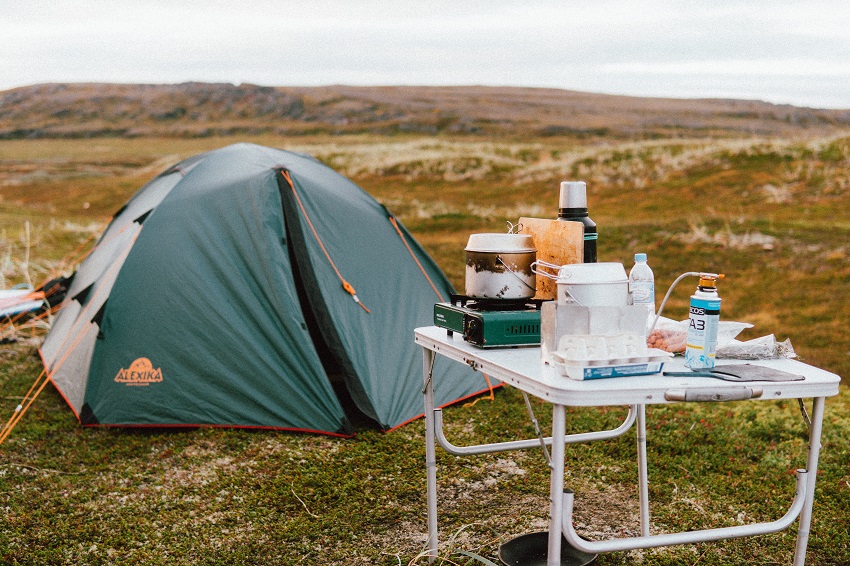 A pitched tent and a table with camping cookware