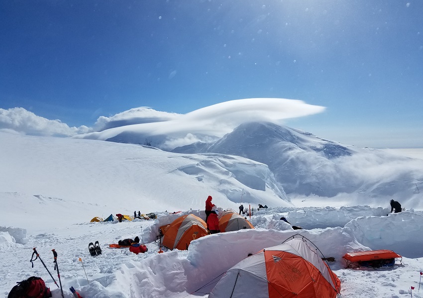 A campsite with multiple tents in snowy mountains