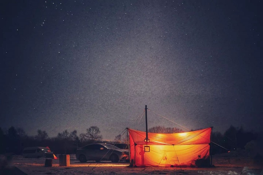 OneTigris TEGIMEN Hammock Hot Tent with lights inside is pitched outdoors at nighttime 