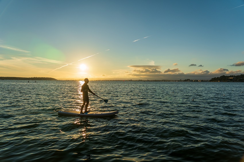 A man paddles a SUP at sunset