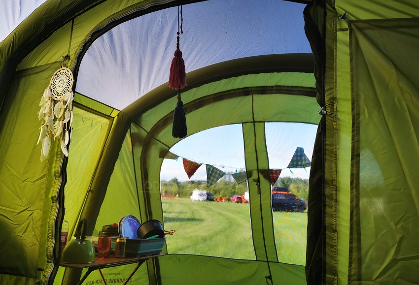 A view from inside of a green tent with a screened room and mesh doors and ceiling