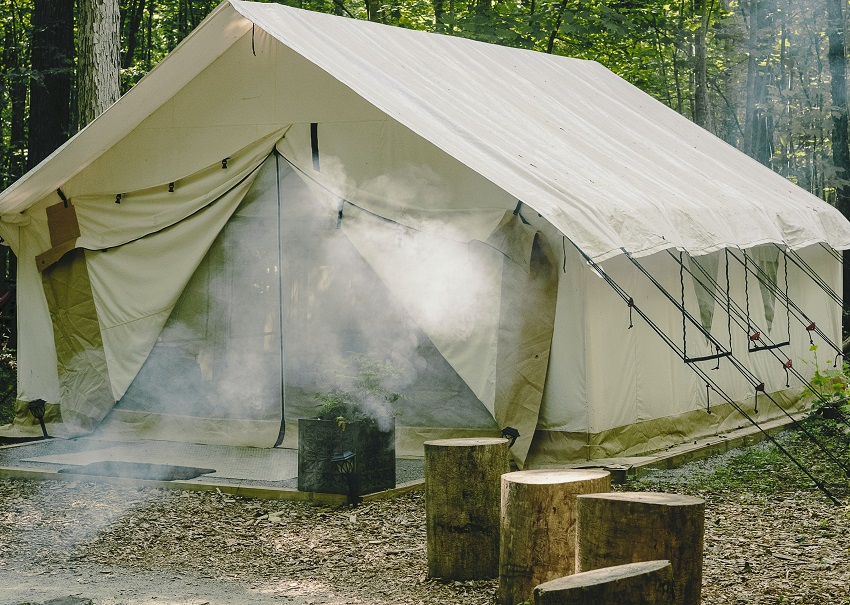 A white canvas tent pitched in the forest