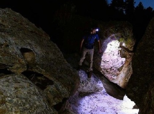 A man with a headlight on his head goes down the rocky path