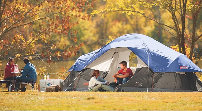 Two couples talk to each other in front of the Coleman 8-Person Red Canyon Car Camping Tent at the beautiful autumn spot