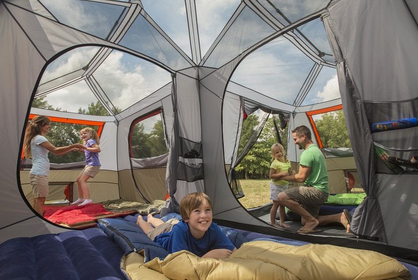 A family plays inside the Ozark Trail 12-Person 3-Room Instant Cabin Tent