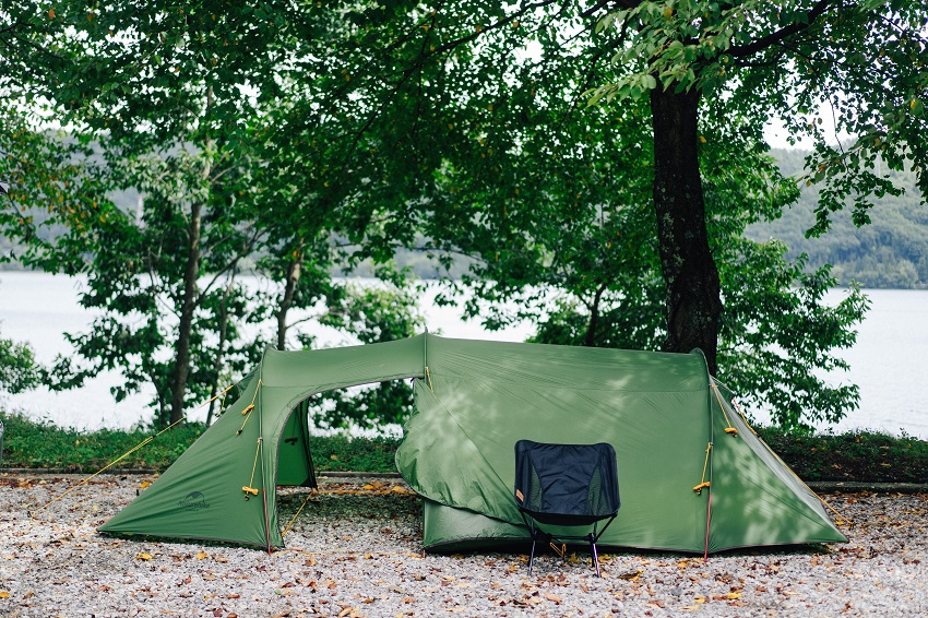 A green tunnel tent pitched under a tree