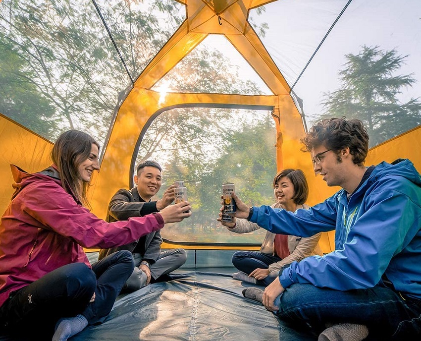 A company of tourists drinks beverages inside the Kazoo 3-4 person family tent