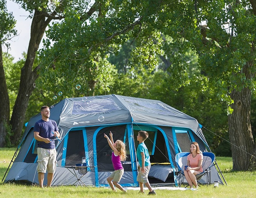 A family plays outside the Ozark Trail 10-Person Dark Rest Tent in the meadow