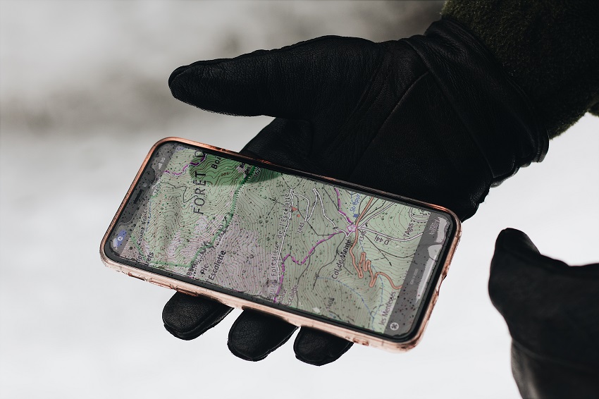 A hand in a glove holds a smartphone with a map